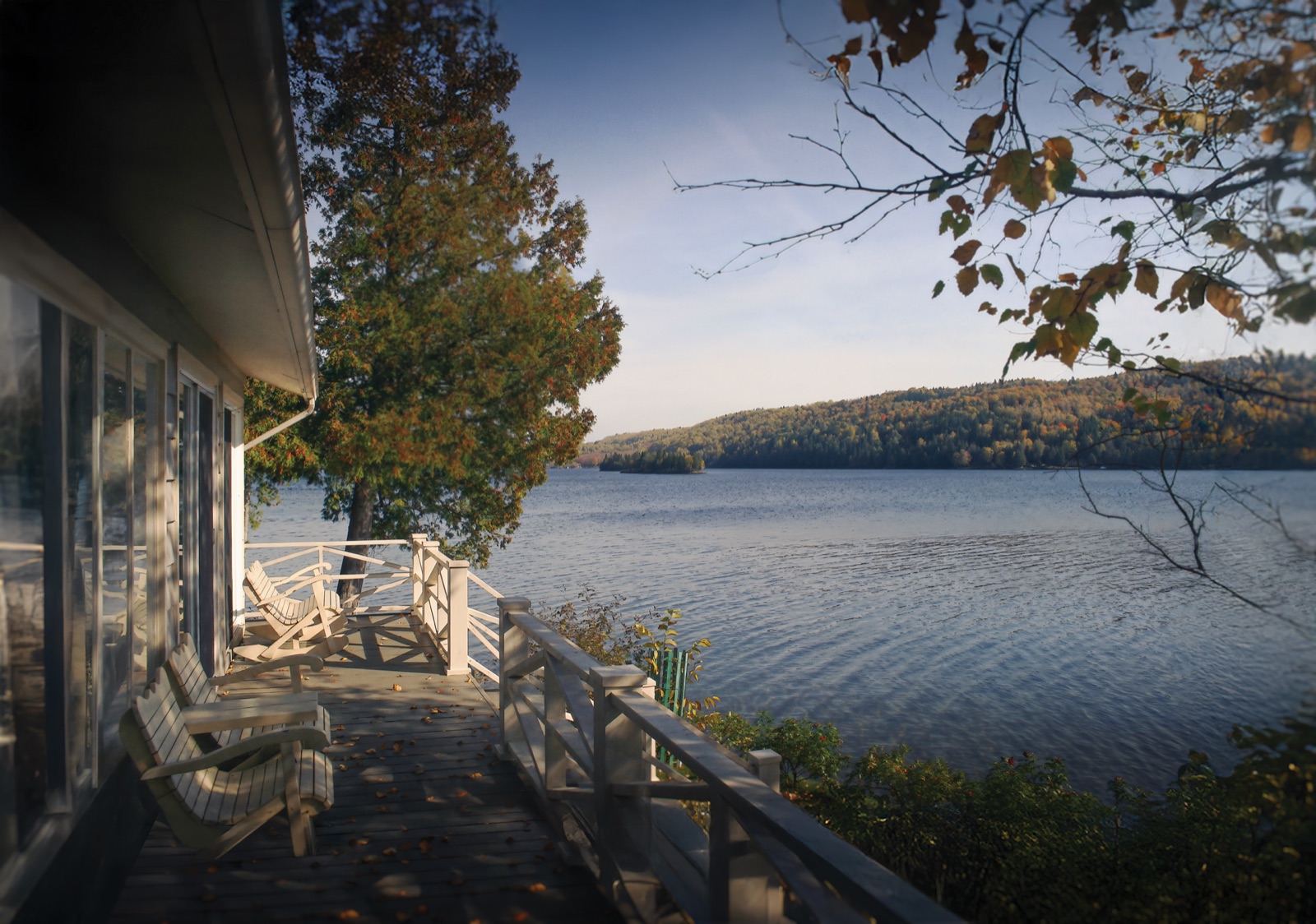 La terrasse du chalet et le lac, entourés des couleurs de l’automne